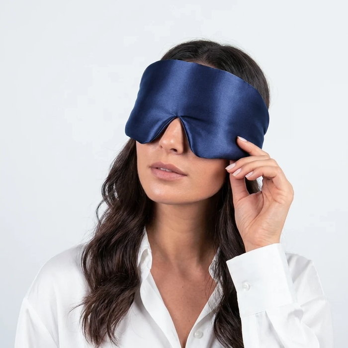 Vrouw schuift haar saffierblauwe zijden slaapmasker omhoog